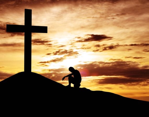 Man sitting desperately under the cross