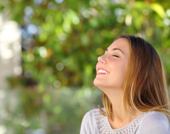 Young happy smiling woman doing deep breath exercises