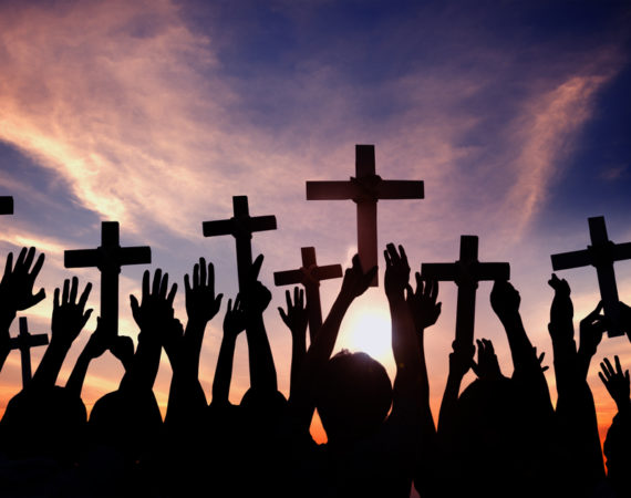 Group of People Holding Cross and Praying in Back Lit