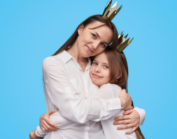 Loving mother and daughter in crowns embracing