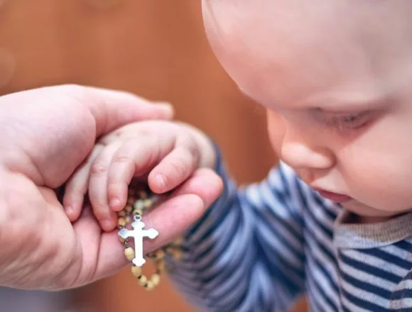 A child takes a rosary from his dad's hand Różaniec siłą rodziny