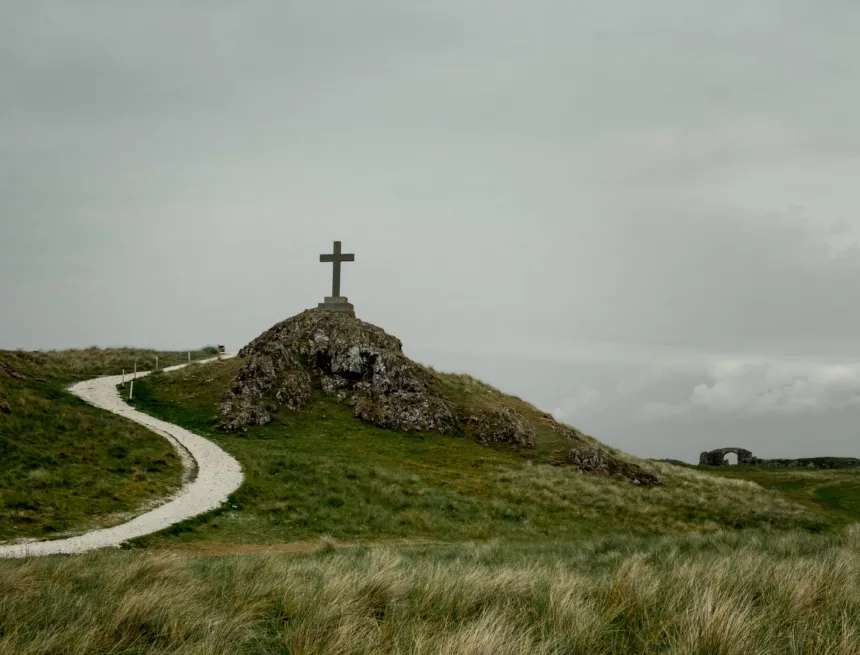 Shot of a cross placed on a pedestal placed on a rocky hill Krótko o doskonałości