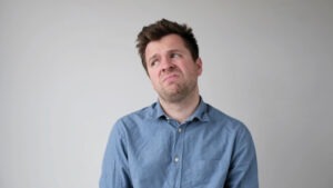 European young man is hesitating and unwilling to make decisions. He is upset about having to do unpleasant work.