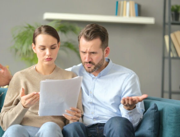Couple having Failure while Reading Documents on Sofa „Instrukcja obsługi” współmałżonka
