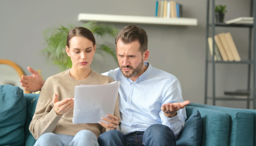 Couple having Failure while Reading Documents on Sofa „Instrukcja obsługi” współmałżonka